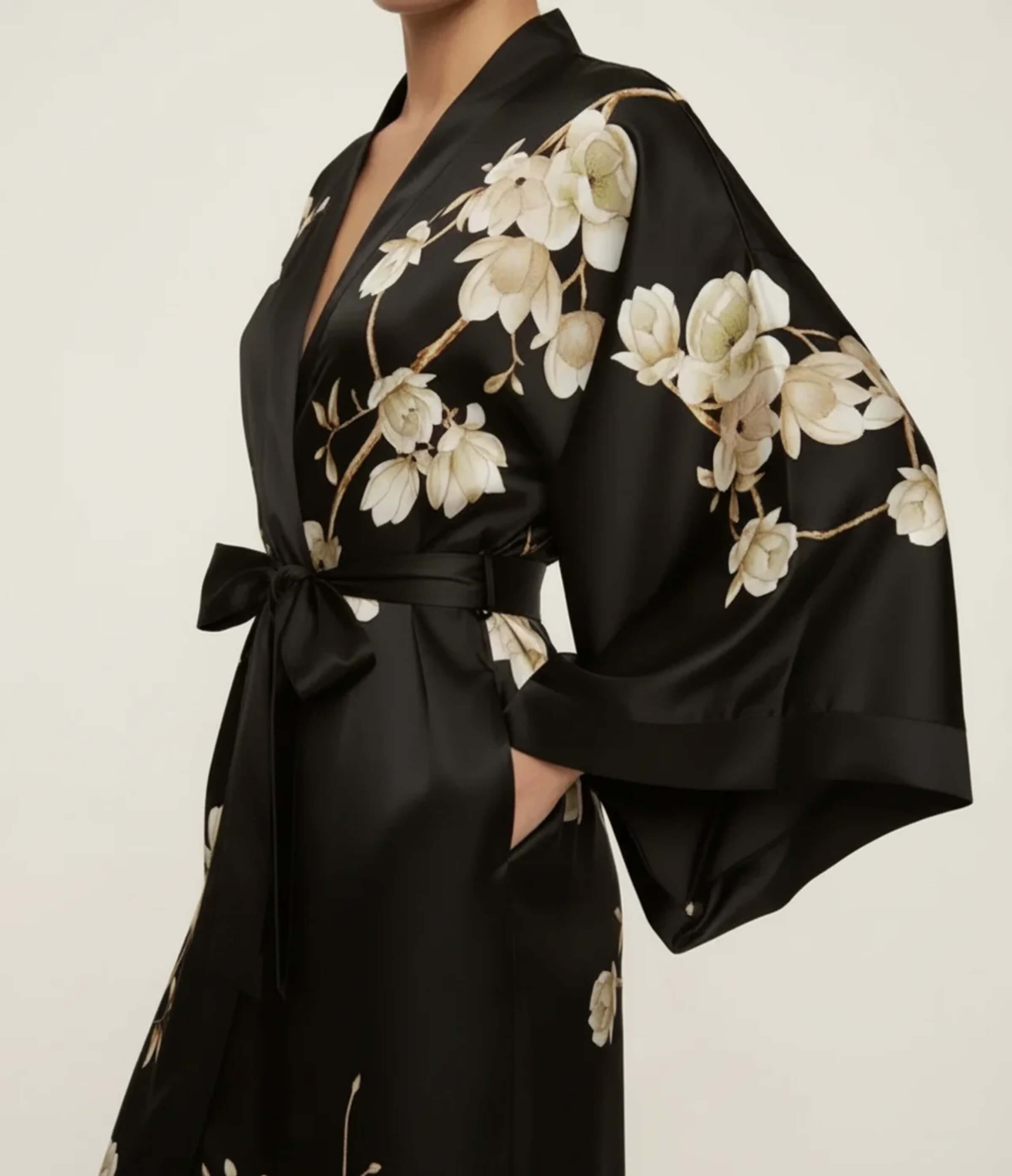 Detail of a black Japanese kimono robe for women featuring elegant floral print on satin fabric with waist belt.