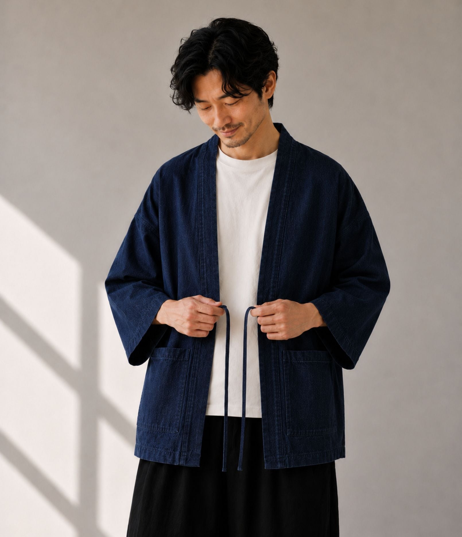 Man tying the himo cords on a navy denim noragi jacket