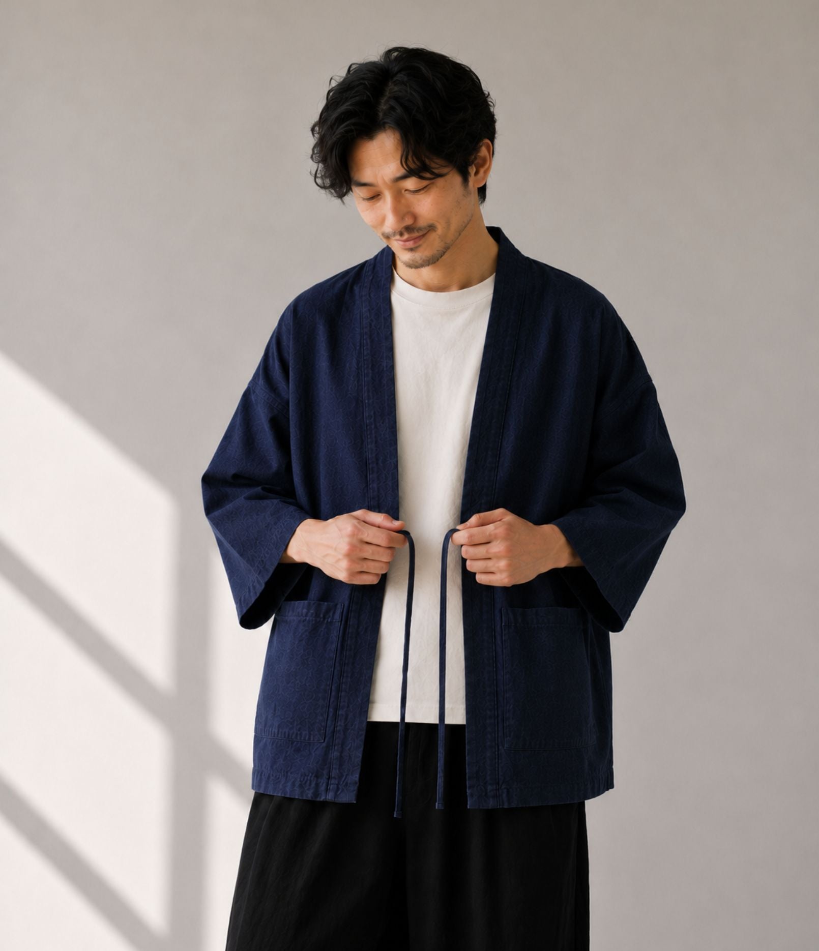 Man tying the himo cords on a navy denim noragi jacket