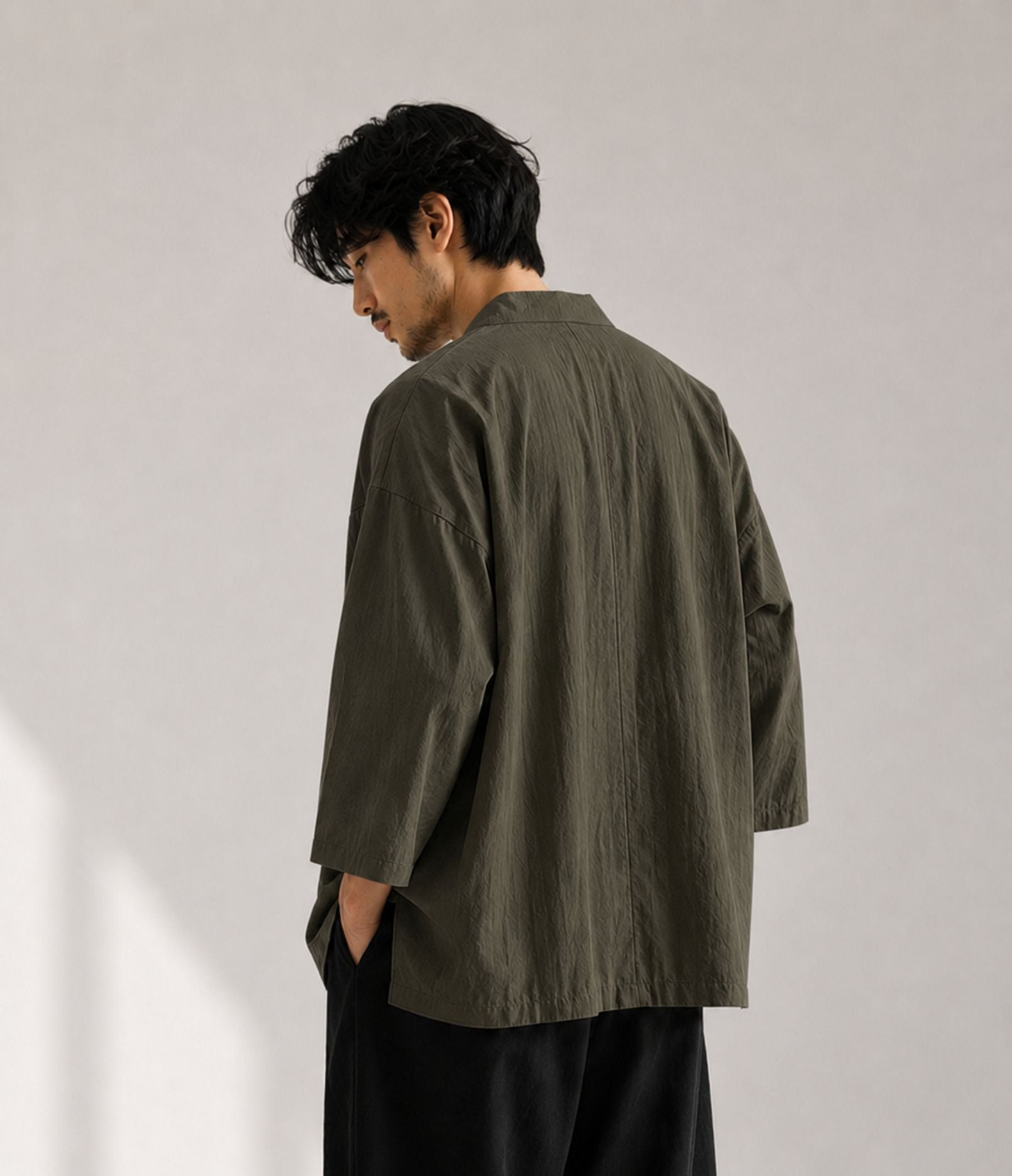 Back view of a man in an oversized khaki Japanese kimono jacket