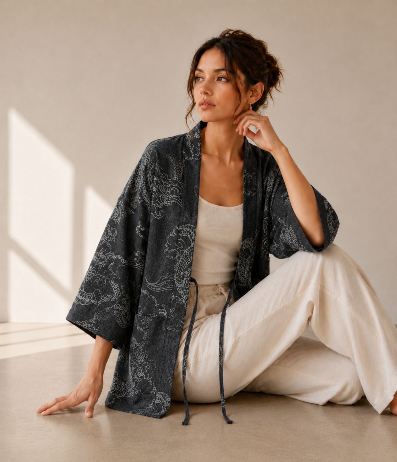 Woman in a charcoal dragon-print haori jacket with tie cords, seated