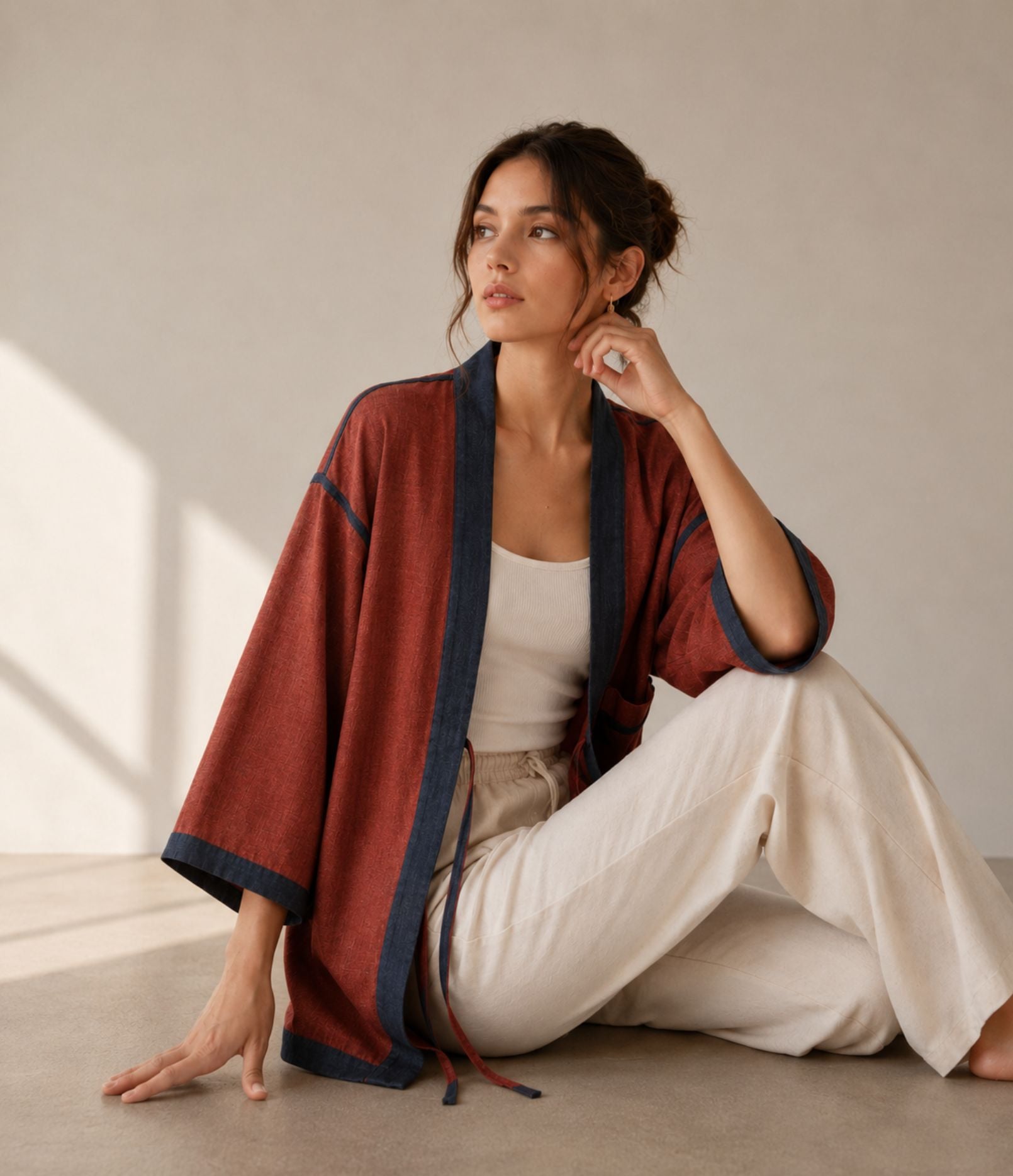 Woman in a rust two-tone haori jacket with navy trim, seated