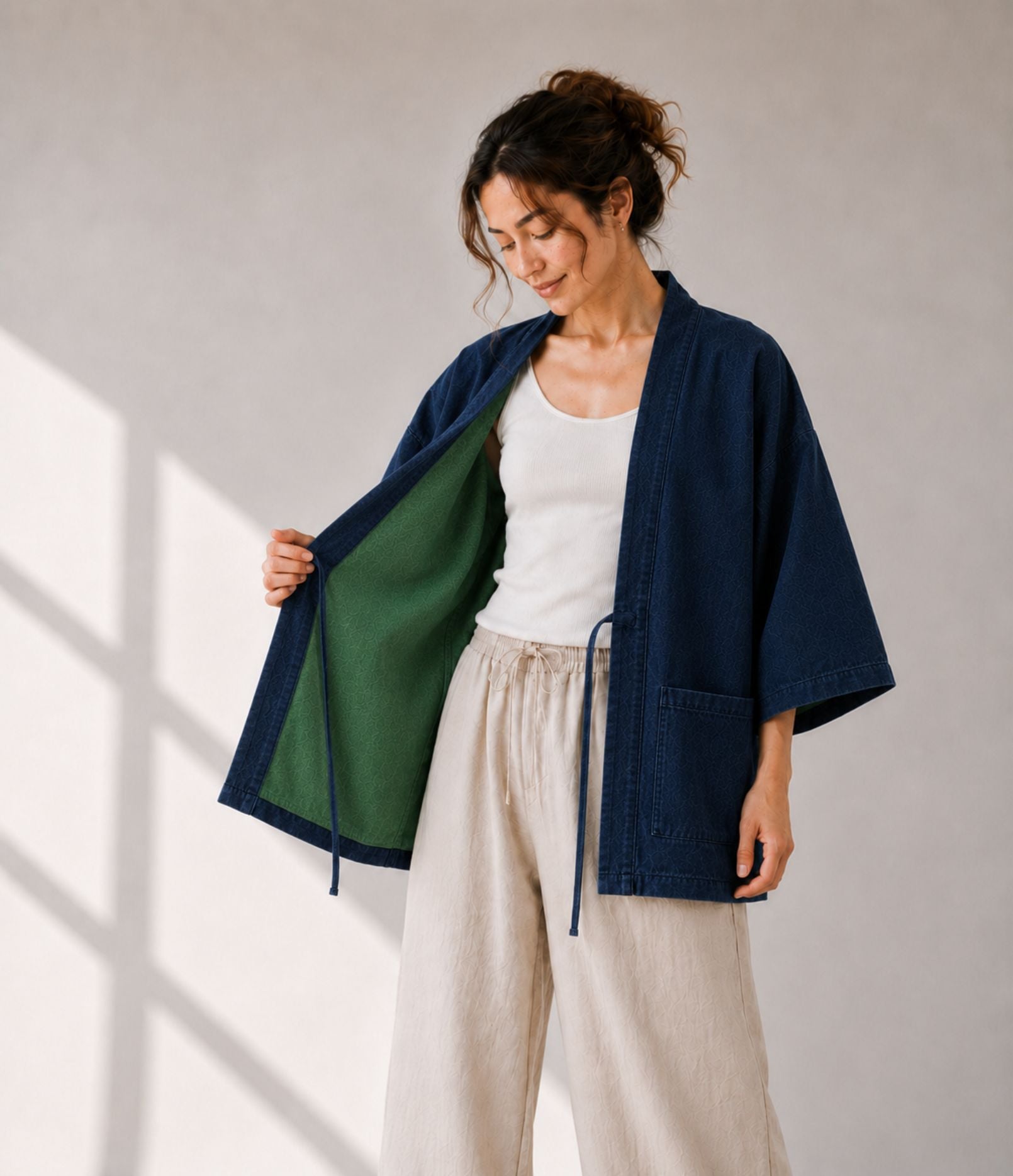 Woman opening a navy haori jacket to show the green reversible lining