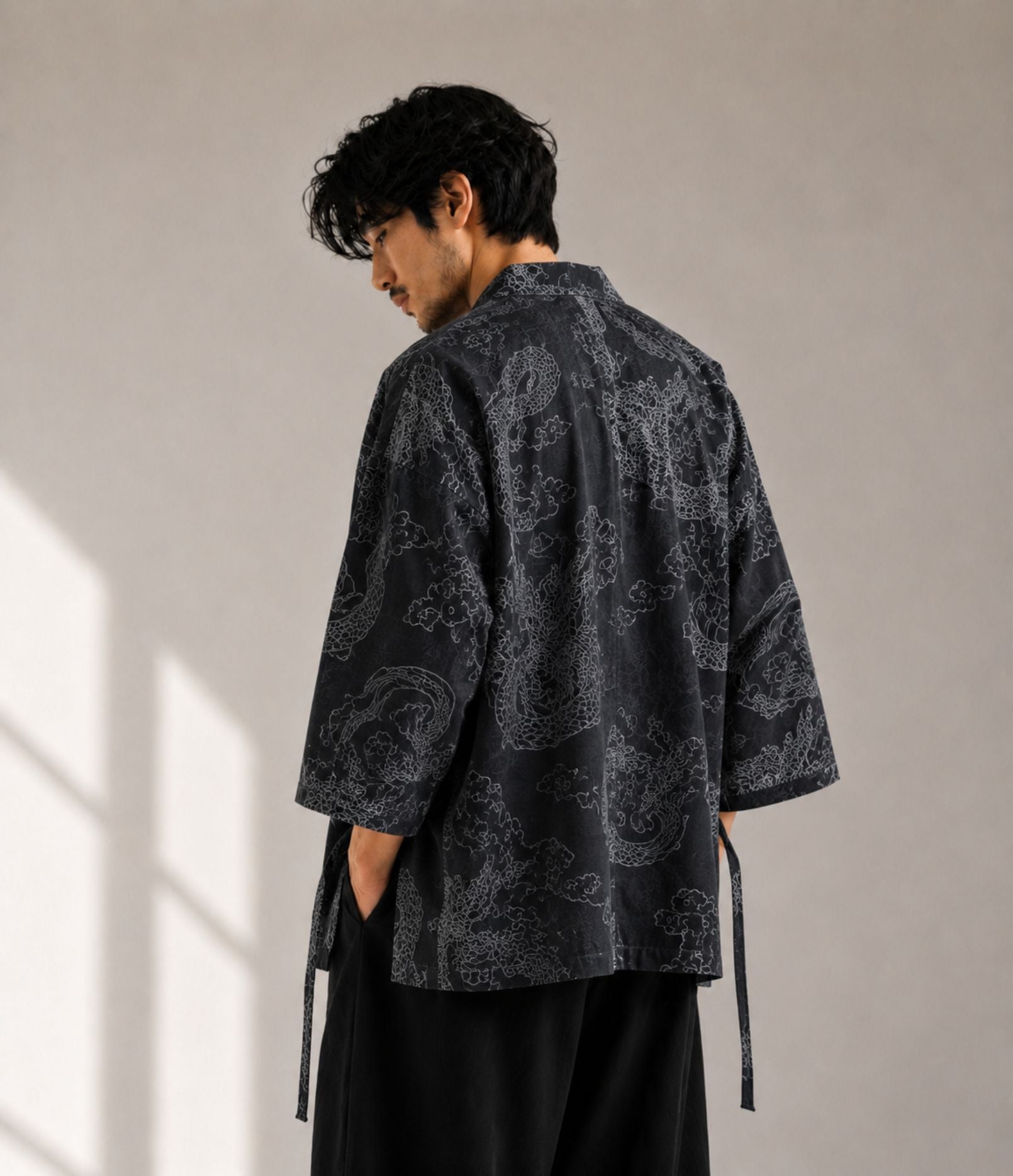 Back view of a man in a charcoal dragon-print kimono cardigan