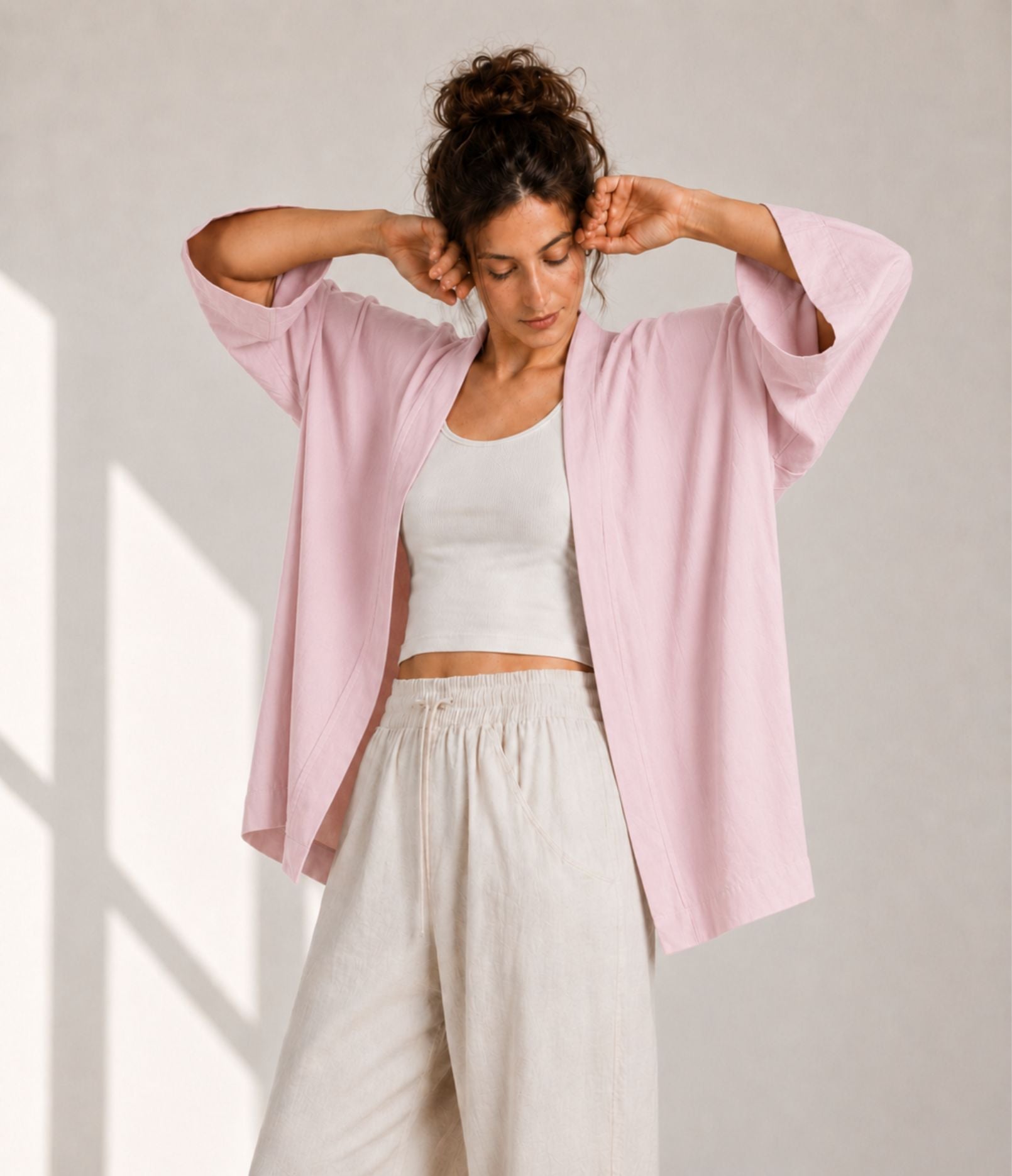 Woman showing the wide three-quarter sleeves of a pink modern haori jacket