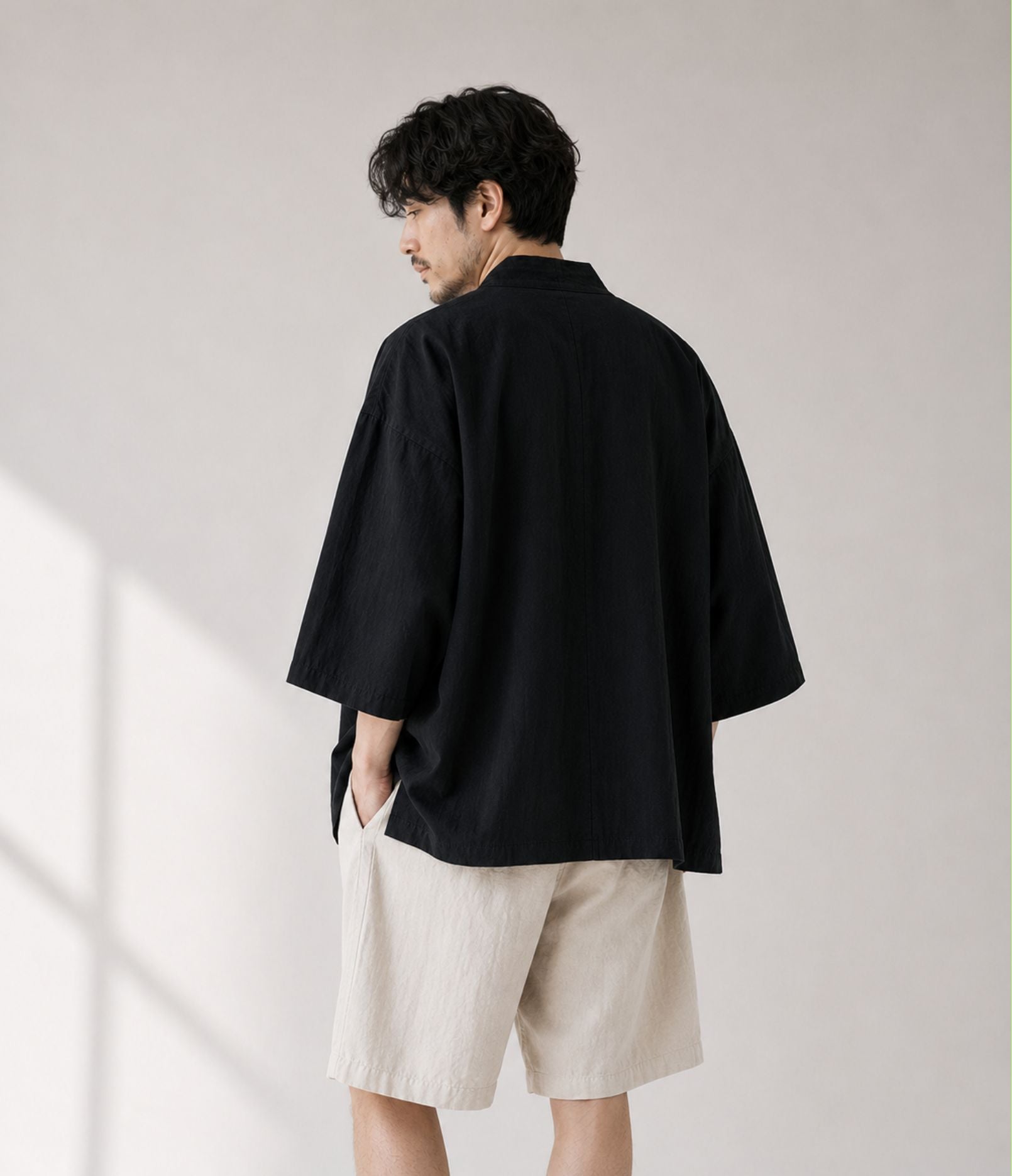 Back view of a man in an oversized black kimono cardigan