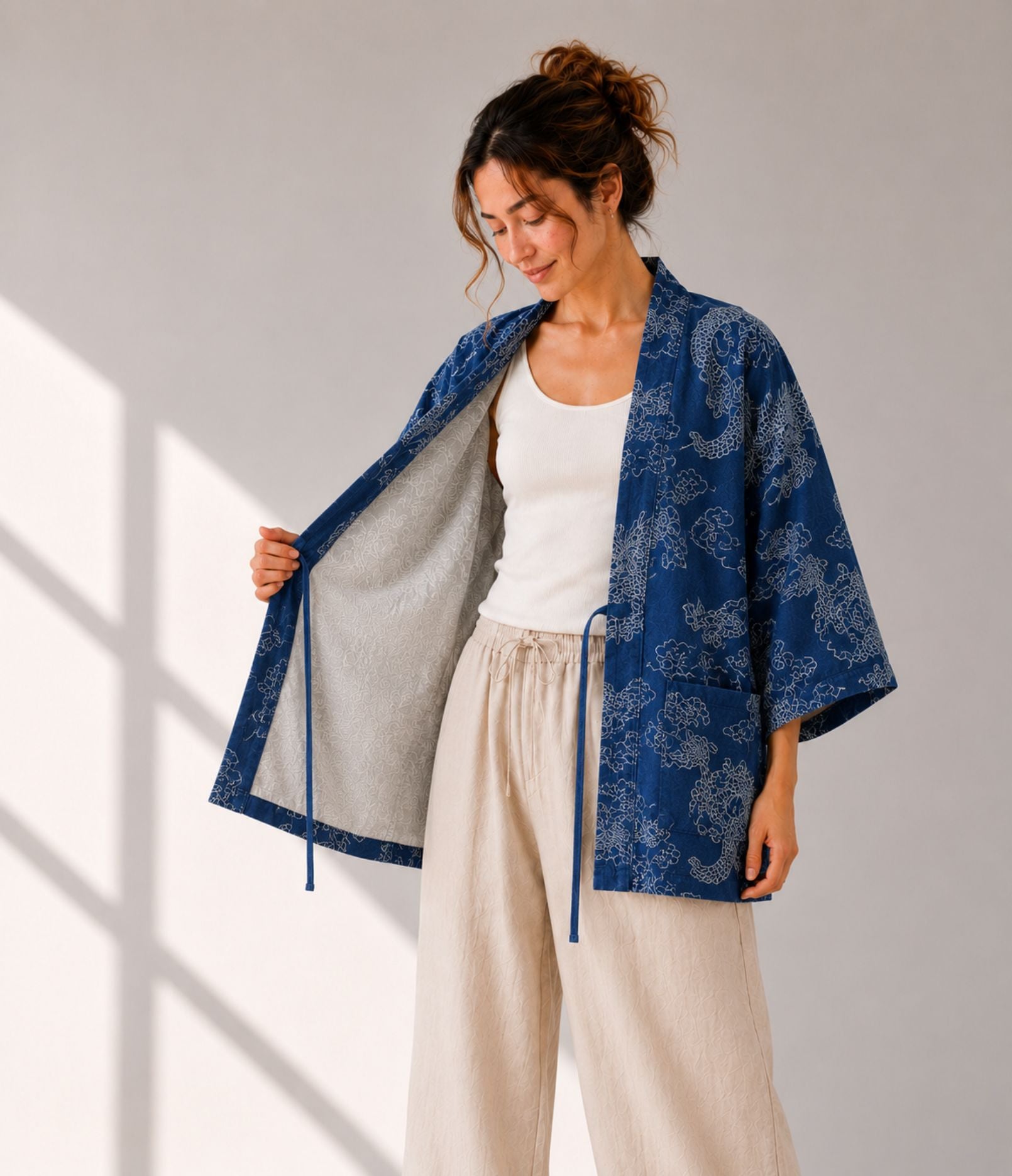 Woman opening an indigo denim dragon-print haori jacket to show grey lining