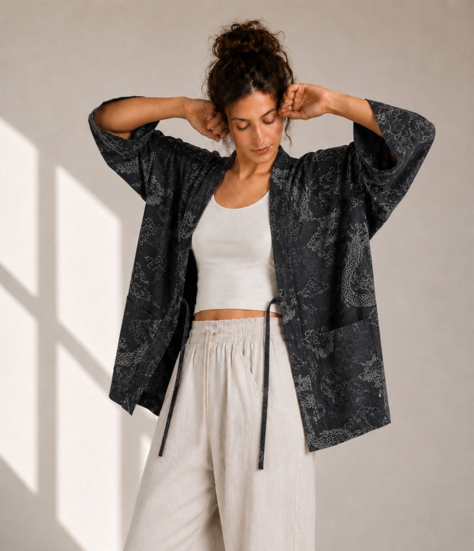 Woman showing the wide sleeves of a charcoal dragon-print kimono cardigan