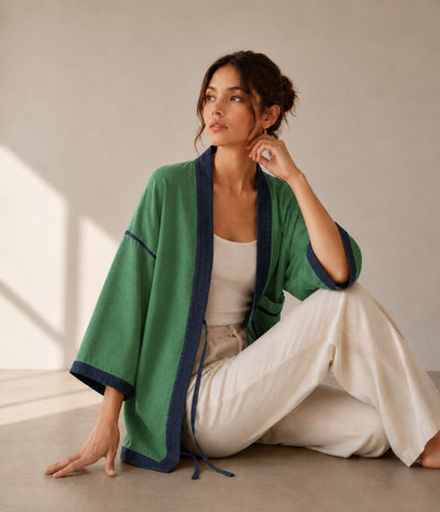 Woman in a green two-tone haori jacket with navy trim, seated
