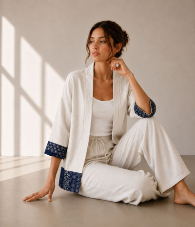 Woman in a natural linen patchwork haori jacket with indigo print trim, seated