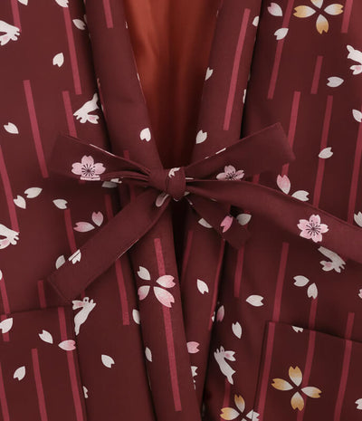 Close-up detail of belt tie on women’s red Japanese hanten jacket with sakura floral pattern