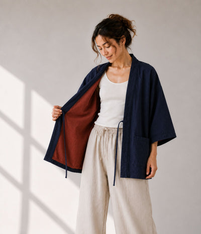Woman opening a navy haori jacket to show the rust reversible lining